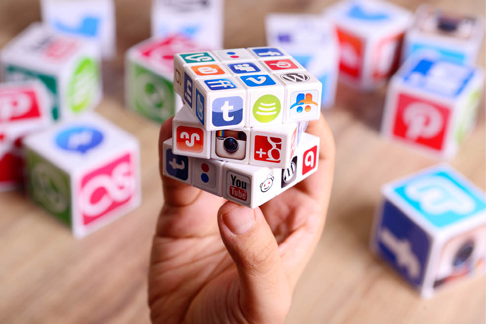  stanbul  Turkey - January 17  2017  Hands holding a Rubik s Cube covered by social media icons on a wooden desk  Paper cubes also with Popular social media services icons  including Facebook  Instagram  Youtube  Twitter 